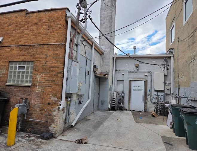 Narrow alleyway between brick and concrete buildings with utility poles.